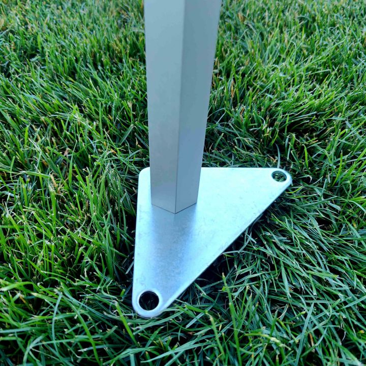Voet van de tentpoot: Detail van de stalen voet waarmee het schaarframe van de tent in het gras wordt verankerd, waardoor de maximale stabiliteit van de hele overkapping bij wind wordt gegarandeerd.
