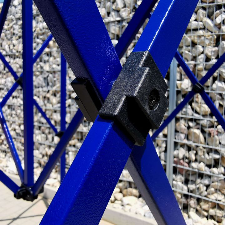 Detail van het zwarte plastic verbindingsonderdeel op de blauwe metalen constructie (stangen) van de tent met schaarmechanisme.